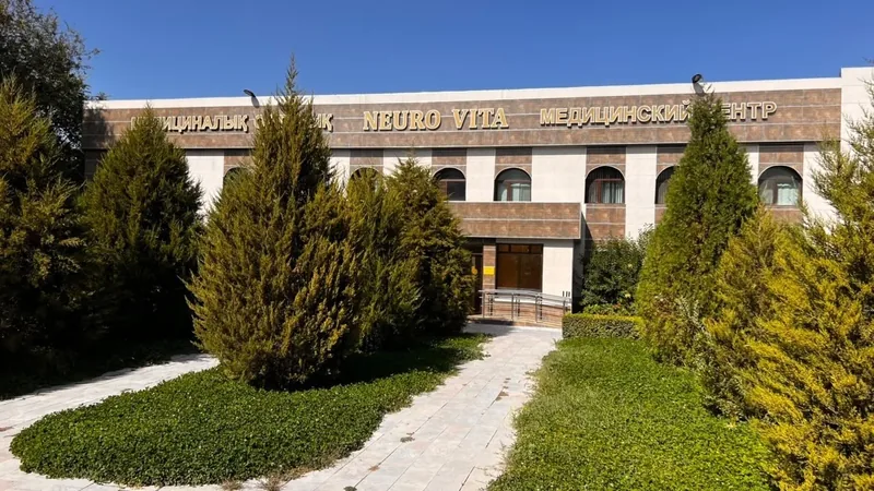 Здание медицинского центра Neuro Vita с вывеской, хвойные деревья у входа